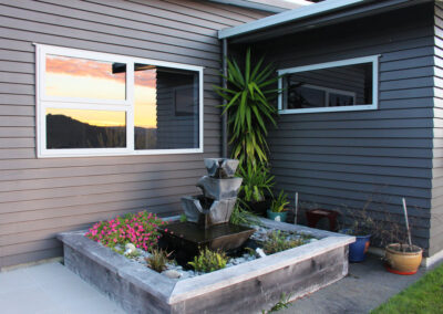A lovely water feature garden built next to a dark grey new build house, all done by Quadrille Construction